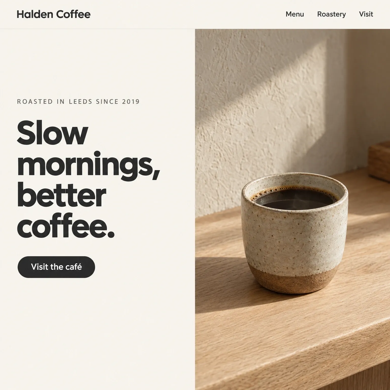 A coffee roastery homepage: warm off-white, a charcoal headline and a photograph of a stoneware cup on an oak counter